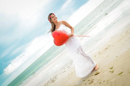 Woman Holding a Heart-shaped Balloon Standing on Seashore