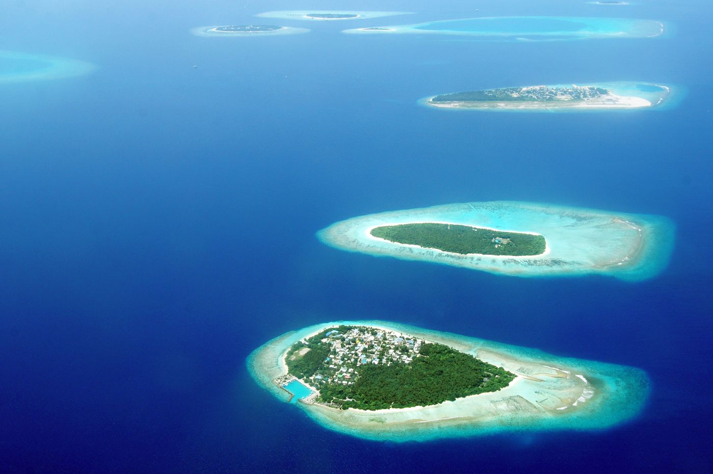 Aerial view of islands in the Maldives ringed by turquoise lagoons and coral reefs