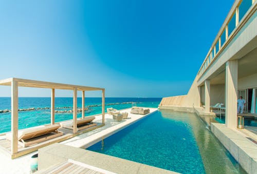 бесплатная архитектурная фотография бассейна из серого гранита и лаунж зоны на пляже Стоковое фото
