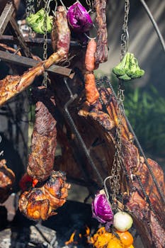 Colorful assortment of meats and vegetables roasting over an open flame, outdoors.