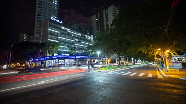 Urban night scene featuring blurred traffic lights and a prominent building in a city.