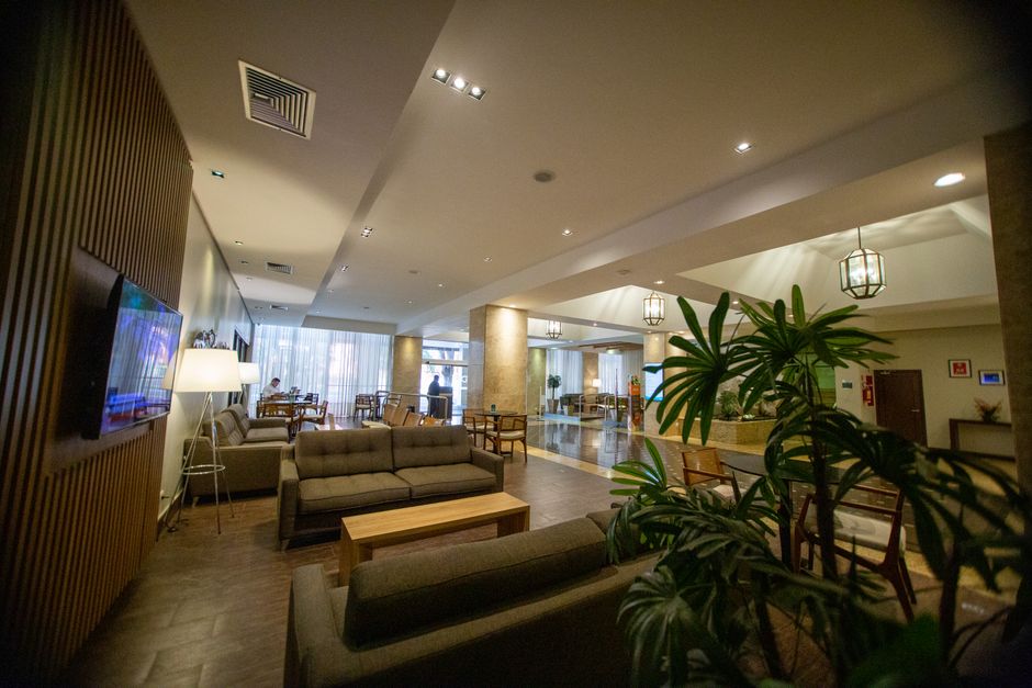 Lobby de hotel moderno e espaçoso, ideal para reuniões de negócios e relaxamento em viagens corporativas.