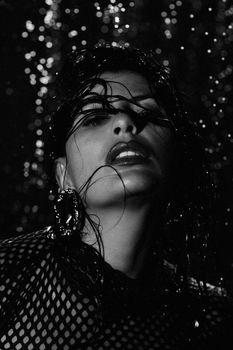 Striking black and white close-up portrait of a woman with wet hair and dramatic lighting.