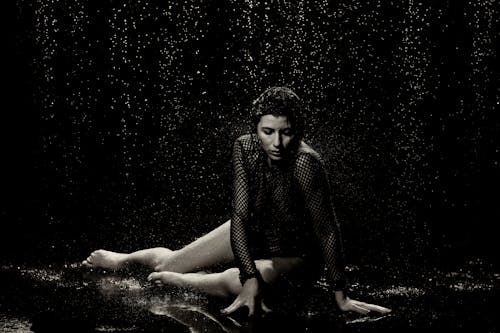 Woman Sitting under Rain in Black and White