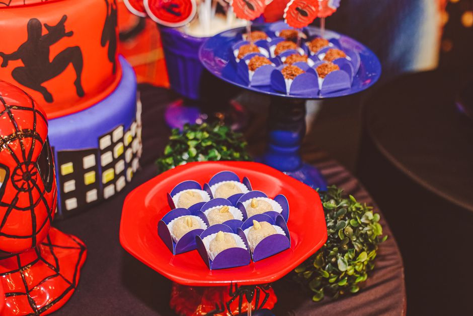 A vibrant Spider-Man themed dessert table with cakes and sweets in comic style decor.