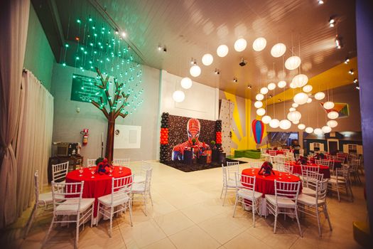 Vibrant indoor event space with themed decor, empty tables, and colorful lighting.