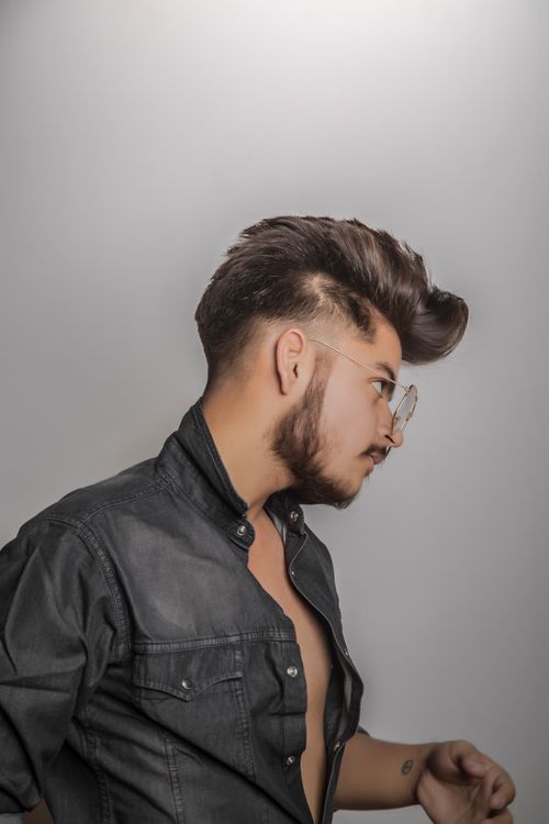 Free Side view of a stylish man with glasses and denim shirt, showcasing trendy hairstyle. Stock Photo