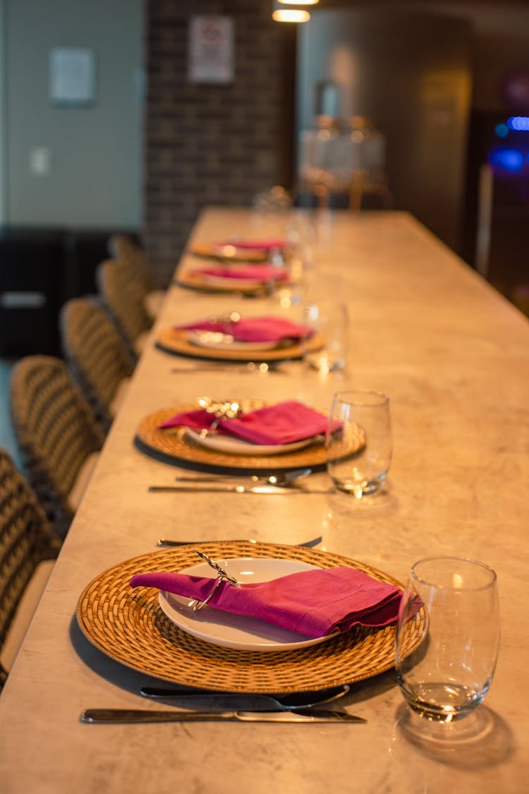 Row Of Empty Plates And Glasses On A Dining Table