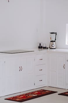 Clean white kitchen corner featuring sleek cabinets and a modern blender.