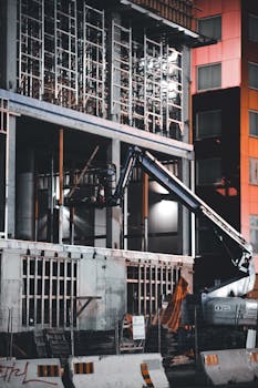 A detailed view of an urban construction site with heavy machinery at night.