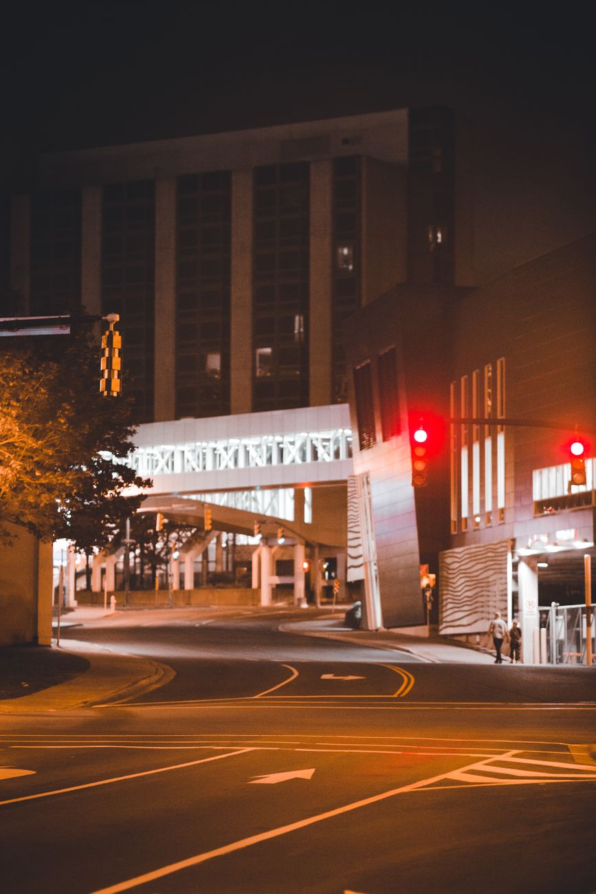 An empty downtown street at night with city buildings and traffic lights, creating a peaceful urban scene.