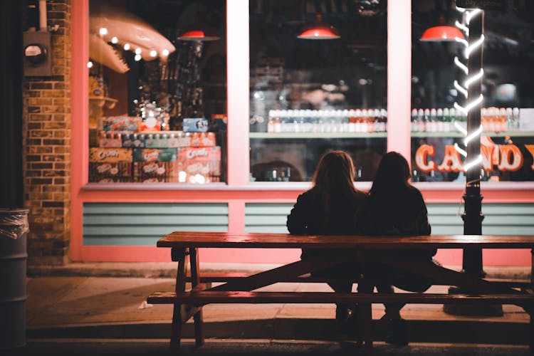 Girls Sitting On Bench On Night City Street