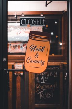 A stylish glass door with closed sign and decorative graphics at a restaurant entrance during nighttime.