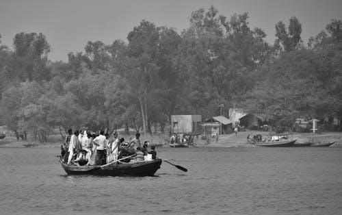 Grayscale Photo of People Riding Boat on Water
