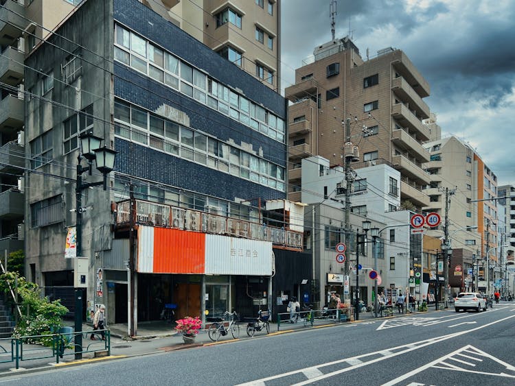 City Buildings Along The Street With People Walking On Sidewalk