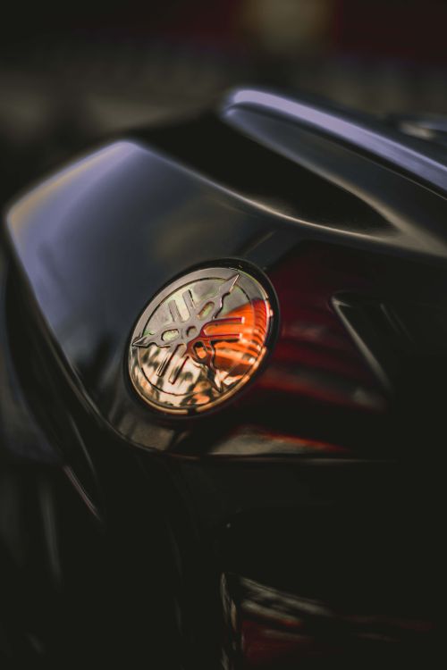 Free Detailed close-up of a chrome motorcycle emblem showcasing selective focus on a dark background. Stock Photo