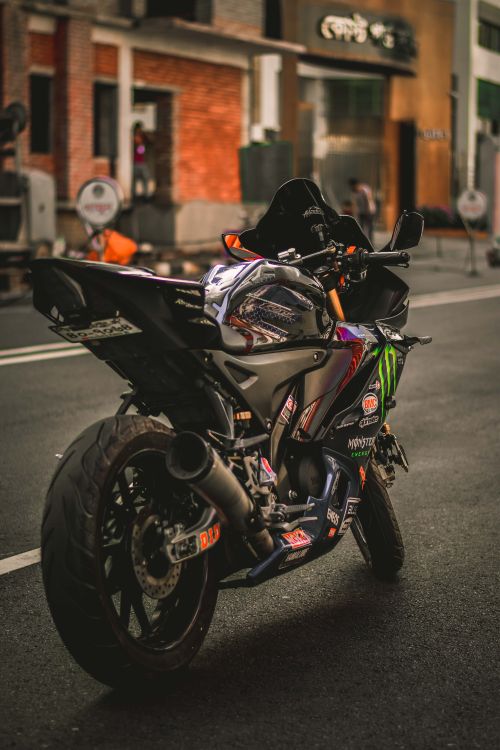 Free A sleek sports motorcycle parked on a city street, showcasing vibrant decals and design. Stock Photo