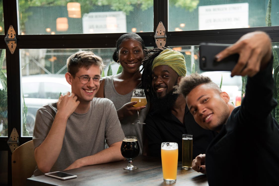 Free Happy multiethnic friends taking selfie on smartphone in cafe Stock Photo
