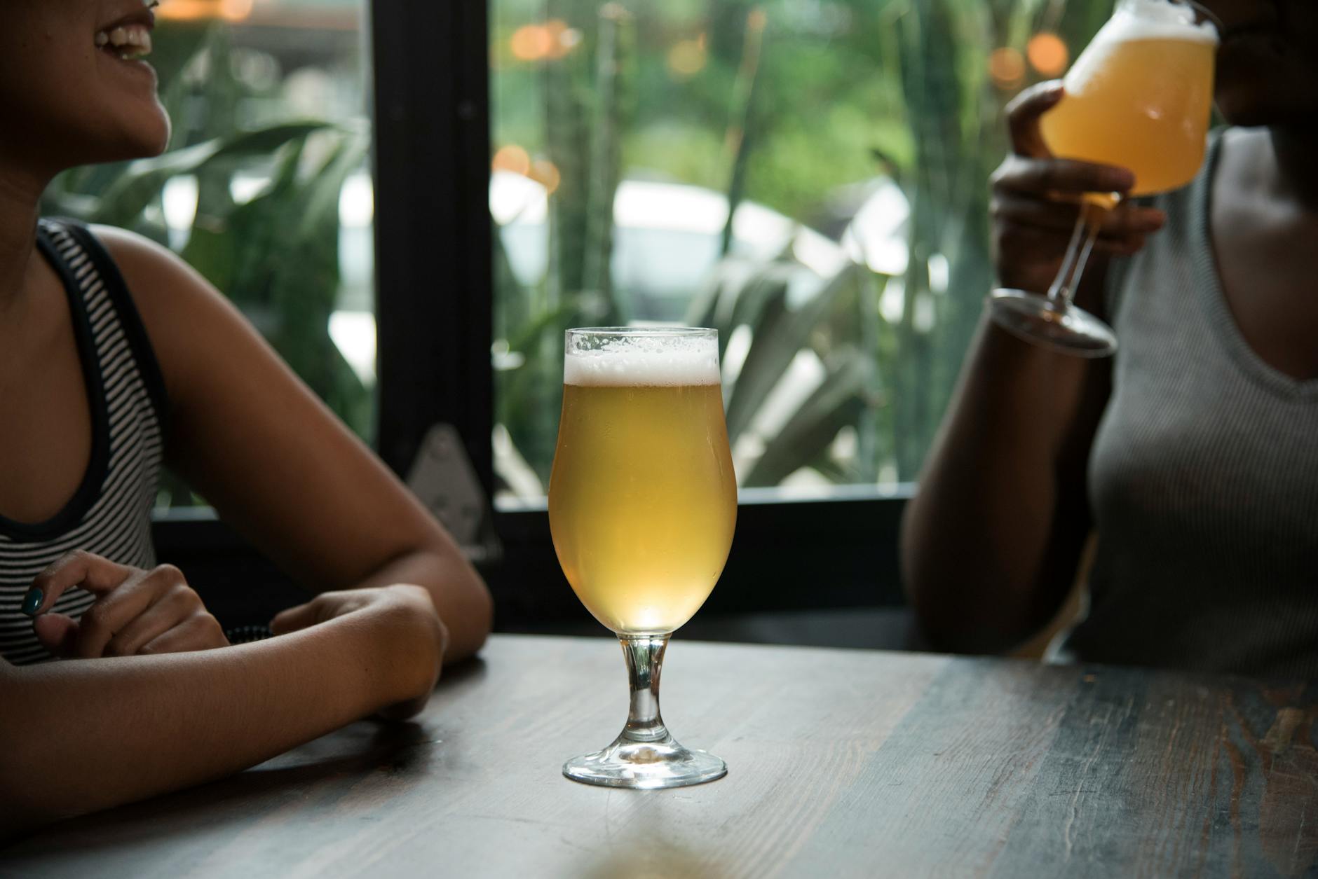 Two women enjoying craft beer in an indoor setting, creating a relaxed social atmosphere.