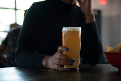 Person Holding Drinking Glass With Orange Liquid