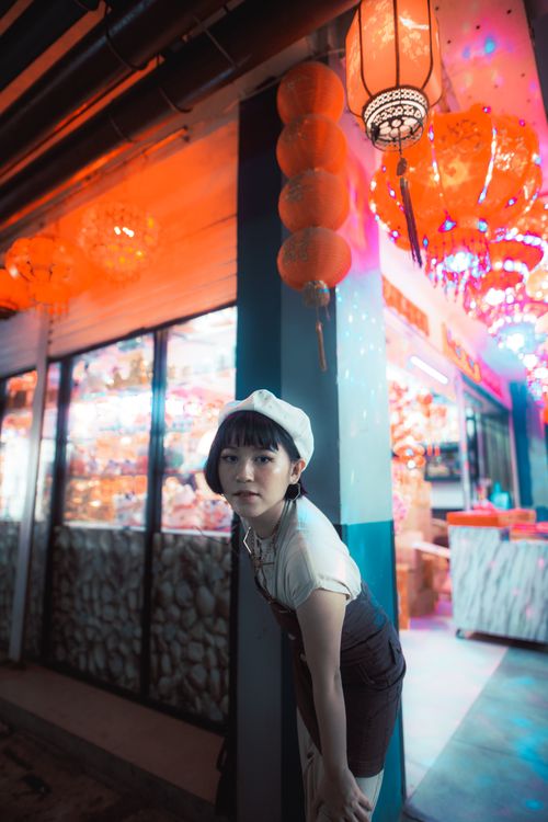 Free Asian woman poses in a colorful urban setting with vibrant lanterns. Stock Photo