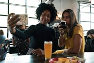 两名女性在舒适的室内环境中喝着饮料自拍，记录美好时光