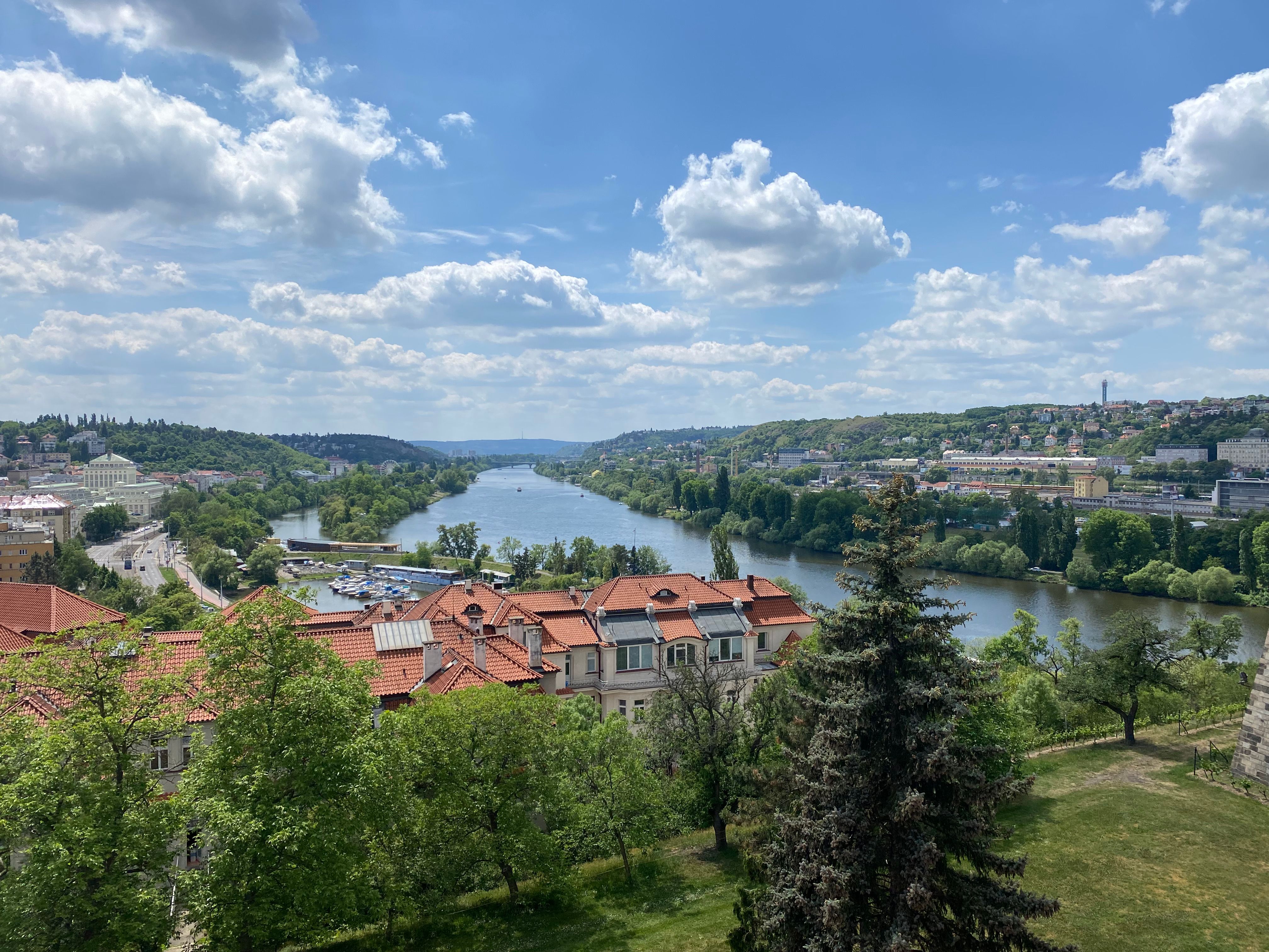 A beautiful aerial shot of the Vltava River surrounded by lush greenery and historic architecture in Prague, Czech Republic.