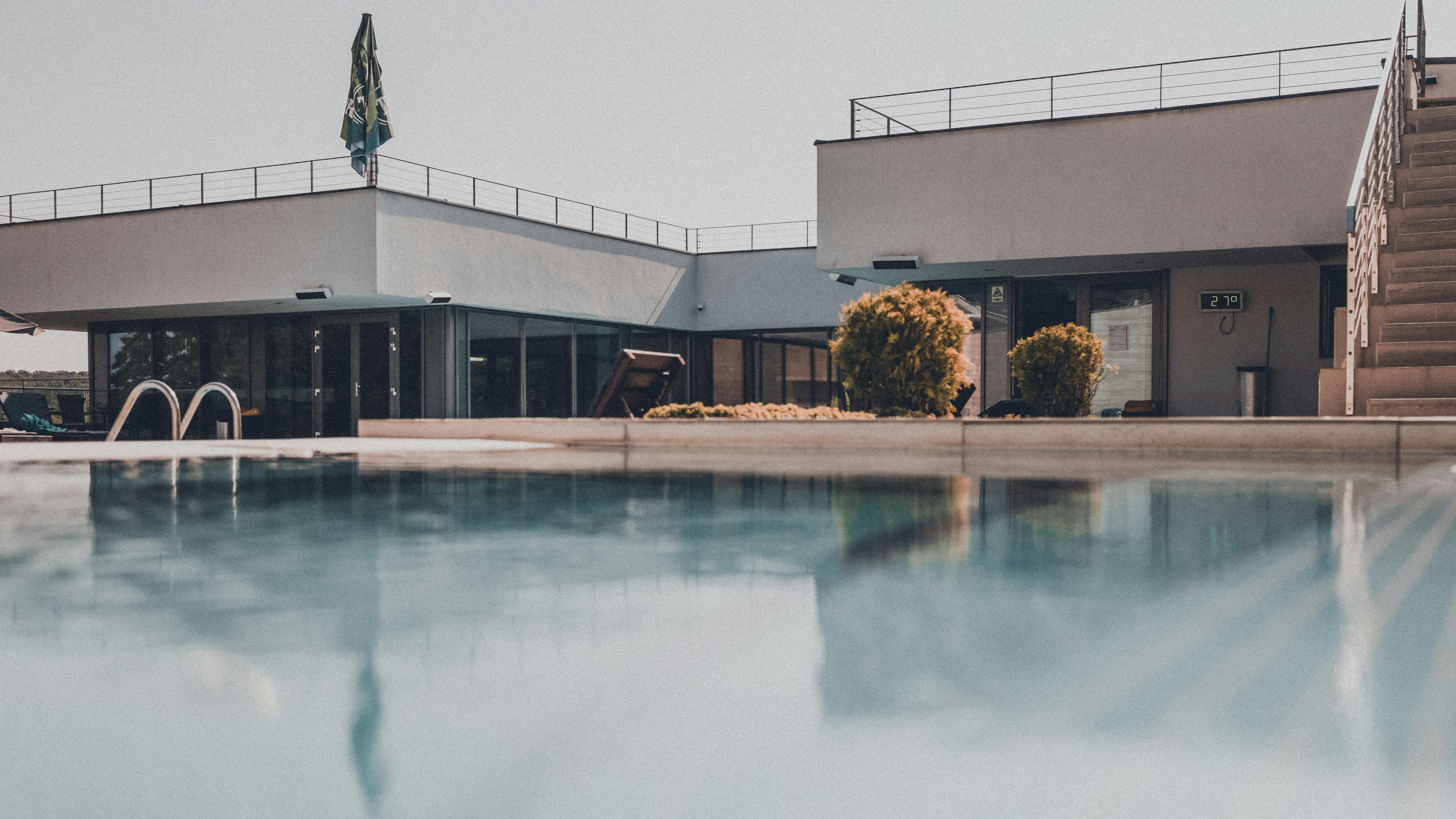 Contemporary building with reflective swimming pool on a sunny day, showcasing modern design.