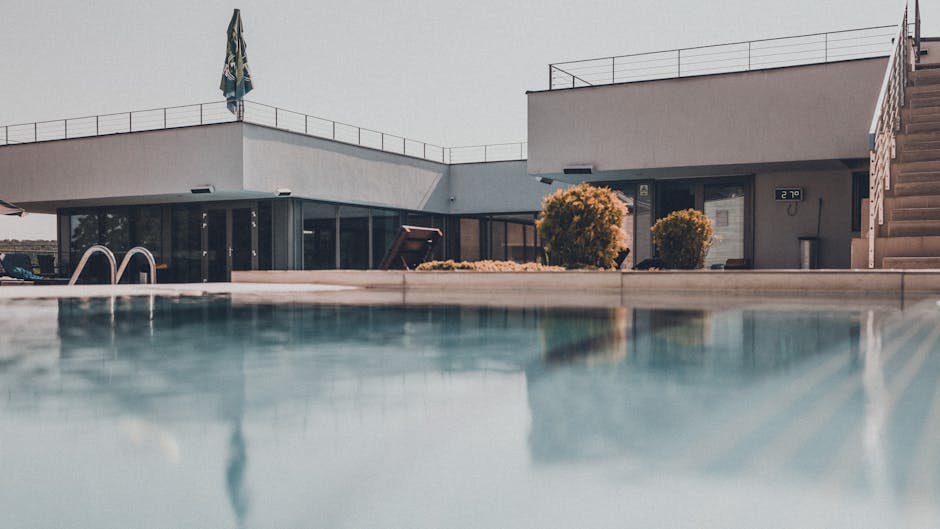 Contemporary building with reflective swimming pool on a sunny day, showcasing modern design.