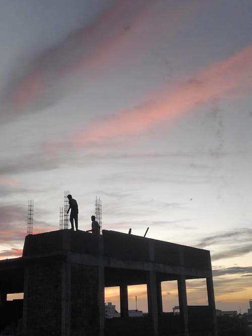 Silhouettes of Men on Building Construction on Sunset