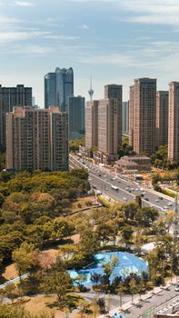 Aerial view of Chengdu skyline with skyscrapers, urban park, and busy streets under a clear sky.