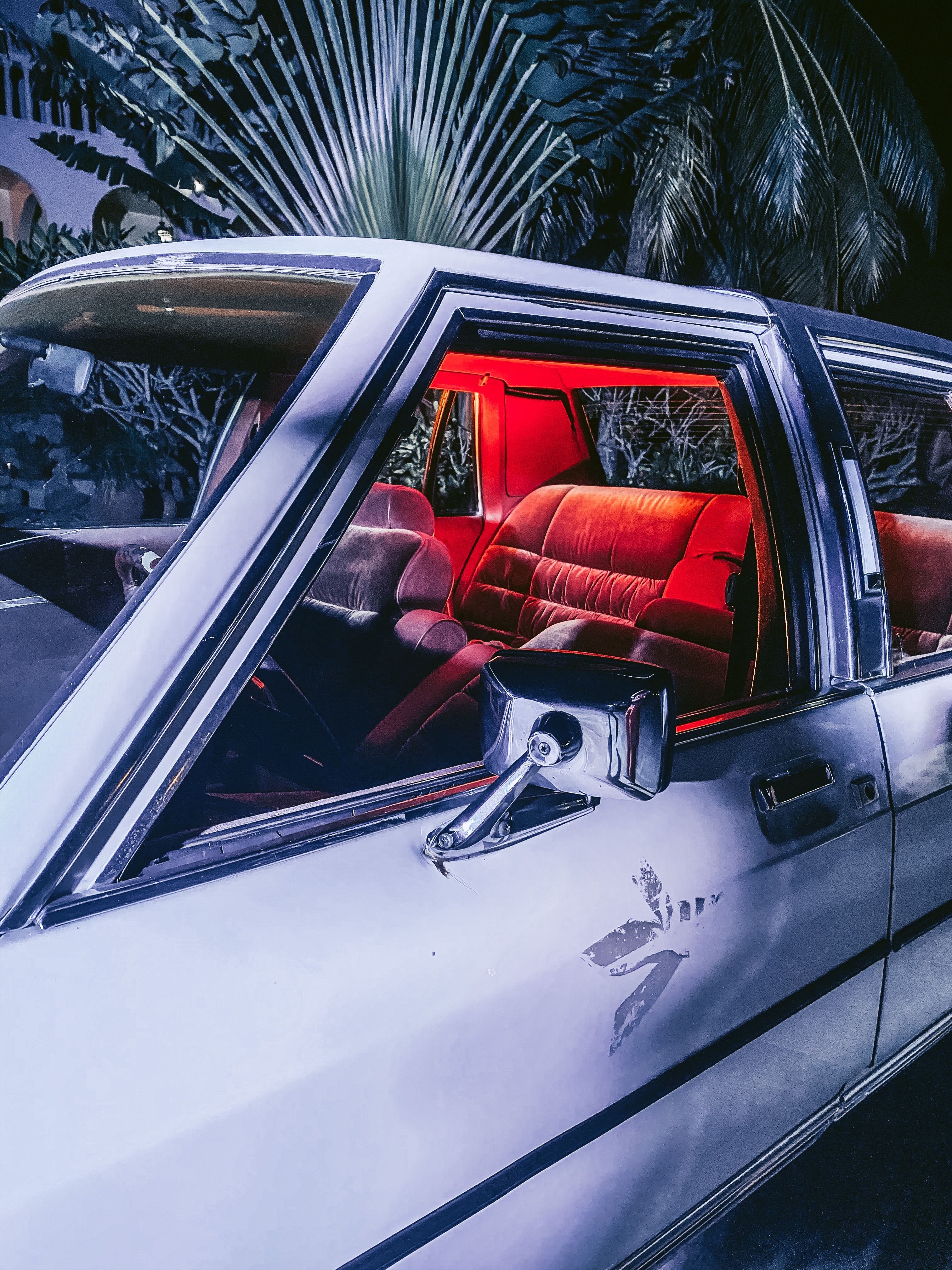 Retro car interior with vibrant red lights and palm trees in Accra, Ghana.