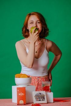 Smiling woman eating an apple, surrounded by vintage kitchen decor, creating a cheerful retro atmosphere.
