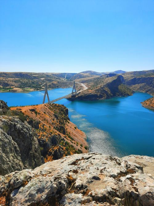 Free Stunning view of a bridge over a bright blue river surrounded by rocky cliffs under a clear sky. Stock Photo