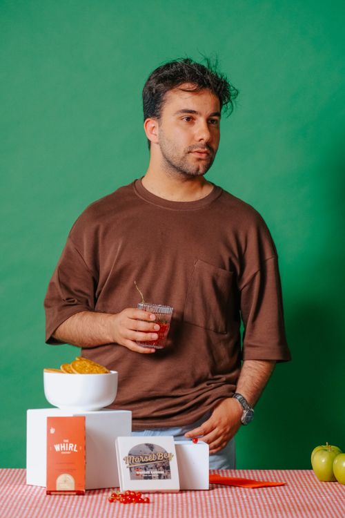 Free Man standing with drink and snacks at a table, set against a vibrant green backdrop. Stock Photo