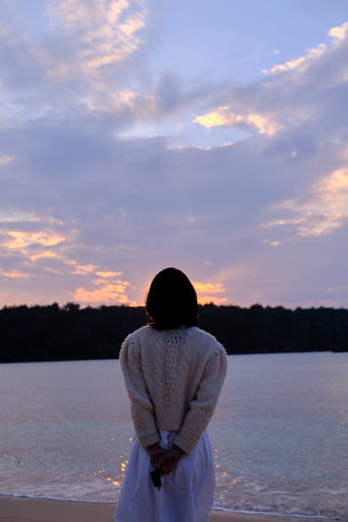 Back View of a Woman Standing on the Beach during Sunset