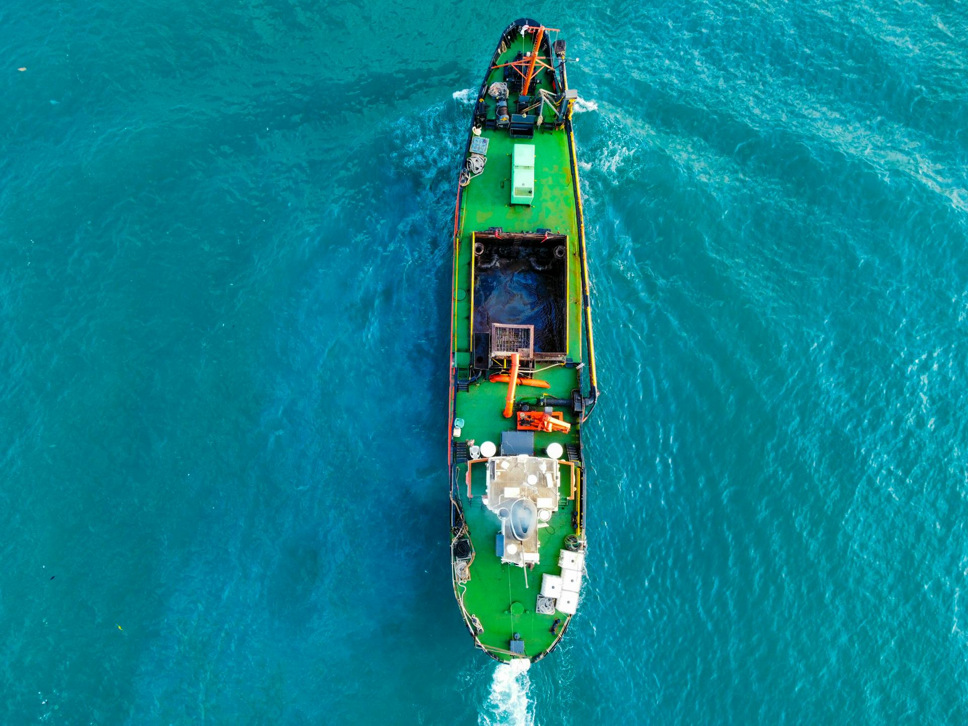 Drone shot capturing a cargo ship sailing through vibrant blue waters, highlighting maritime travel.