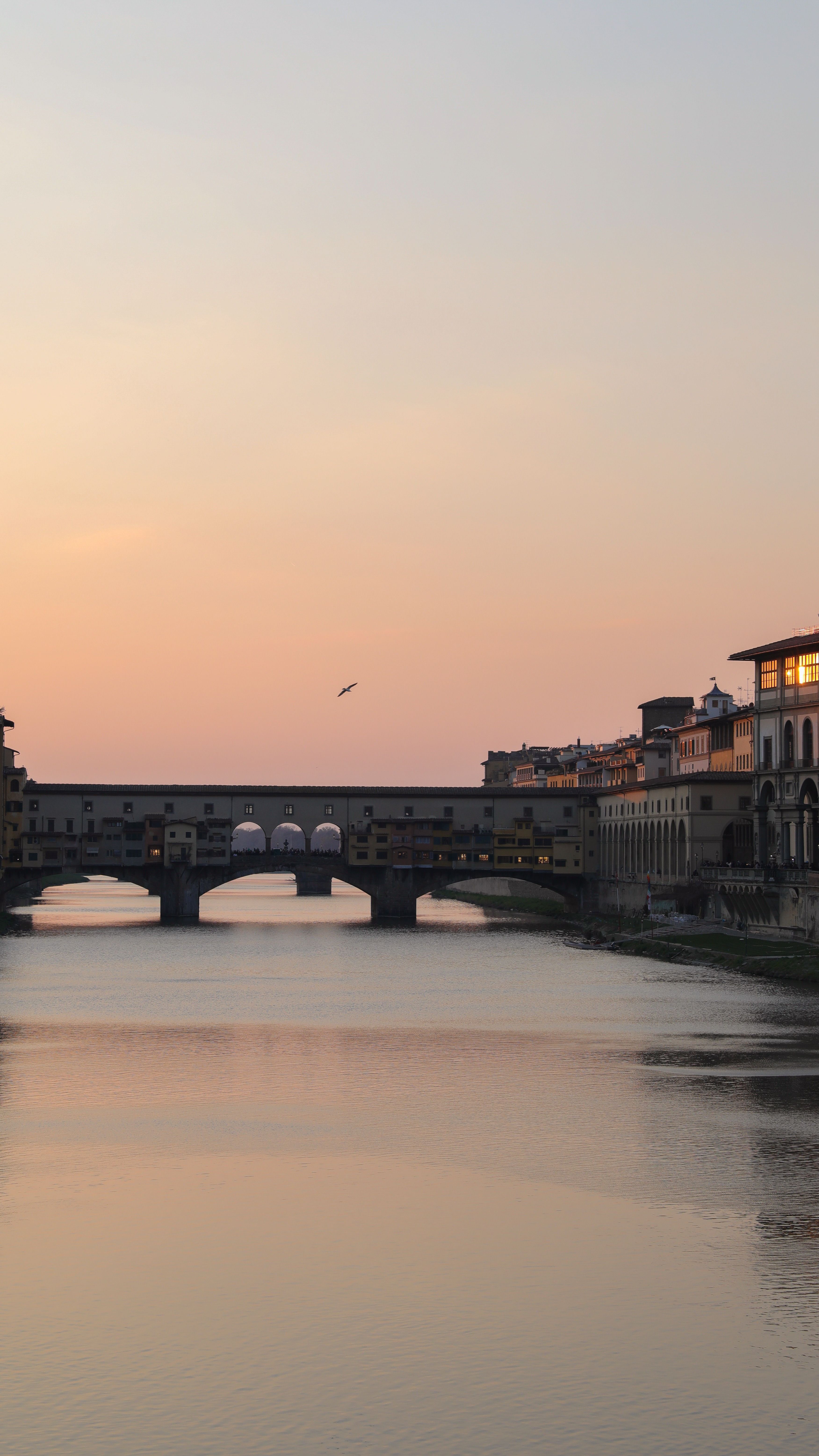 Scenic view of Ponte Vecchio at sunset over the Arno river in Florence, Italy.