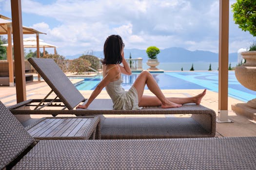A woman enjoying leisure time on a sunbed by an infinity pool with mountain views.
