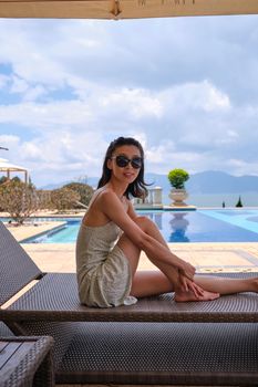 A stylish woman in sunglasses enjoying leisure time on a poolside lounge, embodying vacation vibes.