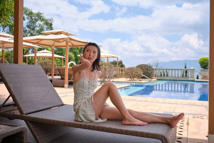 A Woman Sitting On An Outdoor Chaise Lounge Chair