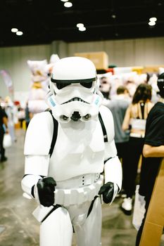Person in stormtrooper costume at a lively pop culture event indoors.