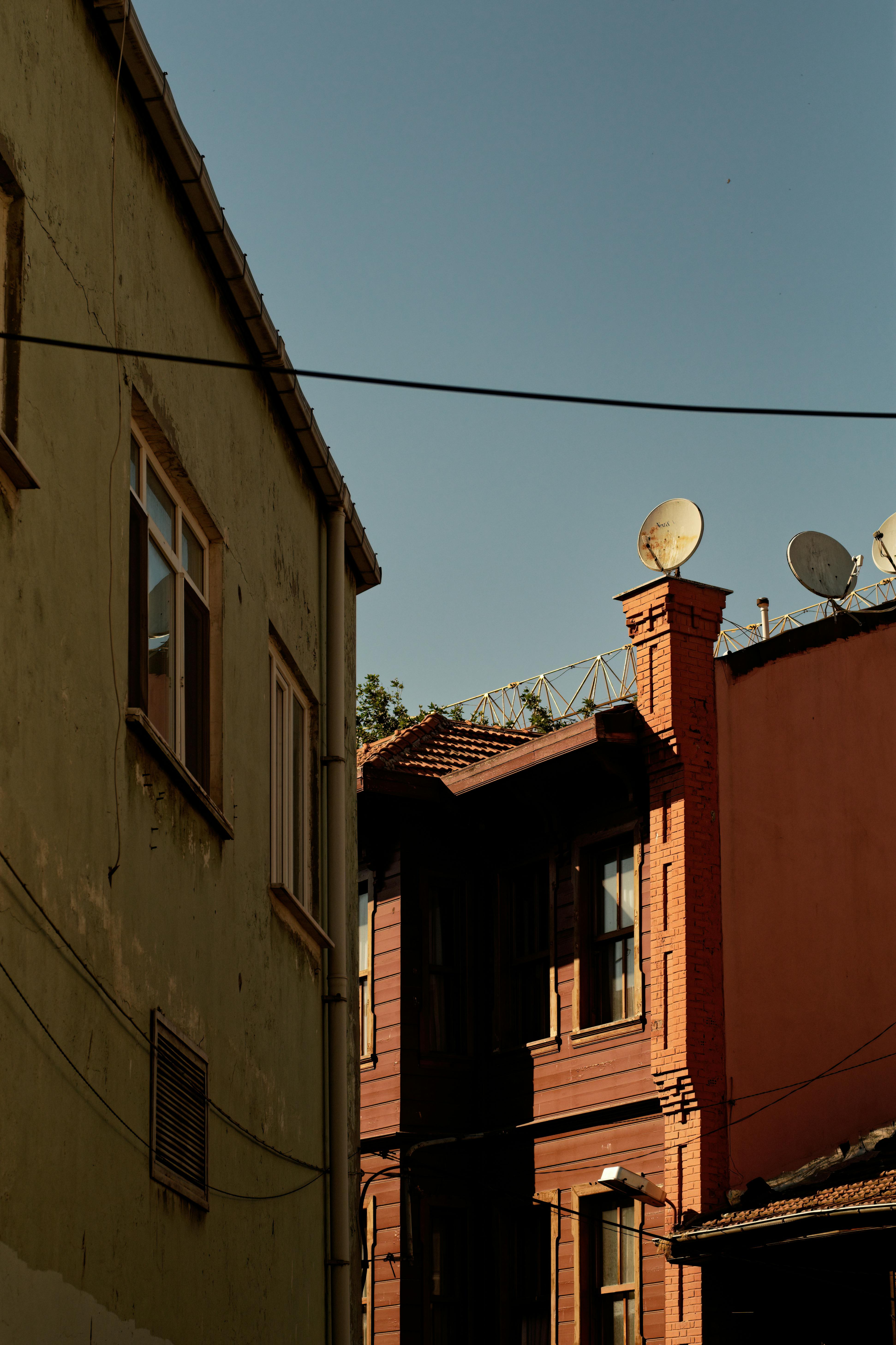 A quiet alleyway with vintage buildings under a clear blue sky, showcasing unique architectural details.