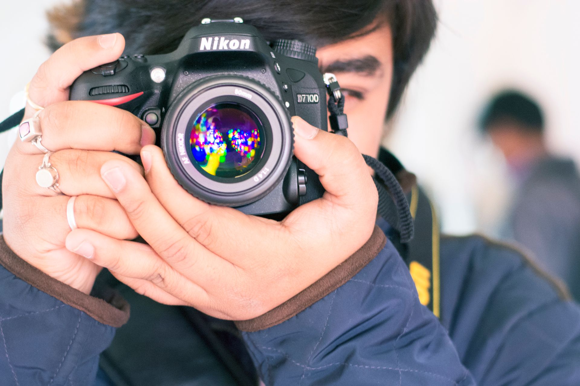 A person holding a Nikon DSLR camera capturing a vibrant image reflection.