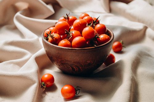 Free A rustic bowl filled with fresh cherry tomatoes on a cloth background. Perfect for food lovers. Stock Photo