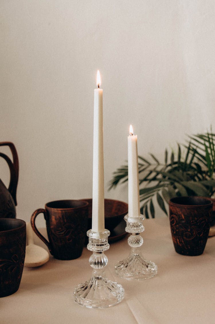 Candles In Candle Holders And Mugs On A Table