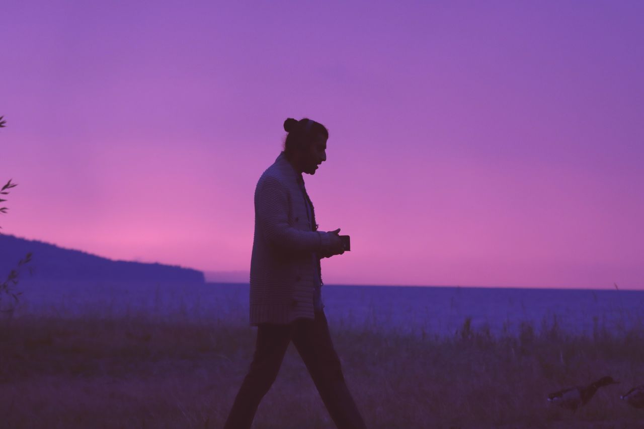 silhouette of a person walking on a beach at purple sunset in j nk pin