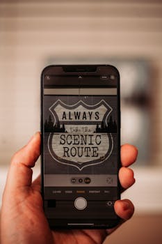 Close-up of a hand holding a smartphone displaying 'Always take the scenic route' message.