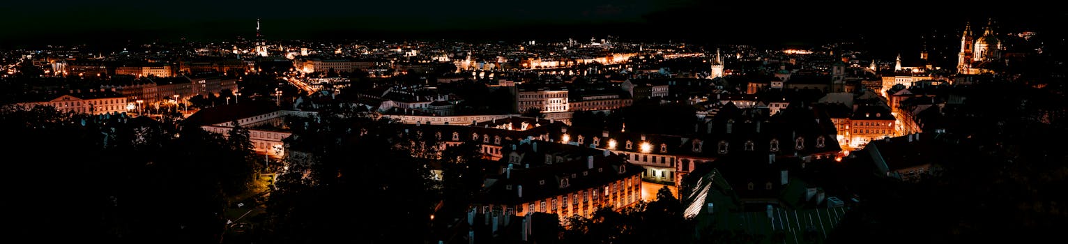 Panoramic nighttime cityscape showcasing illuminated historic architecture and vibrant lights.