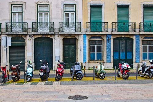 Free A row of colorful motorcycles parked in front of traditional Lisbon building with balconies. Stock Photo